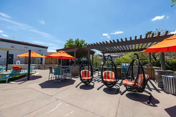 A patio with orange umbrellas and chairs.