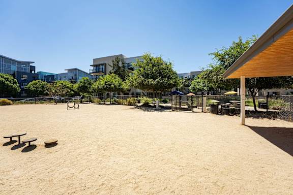 A sandy area with picnic tables and a playground.