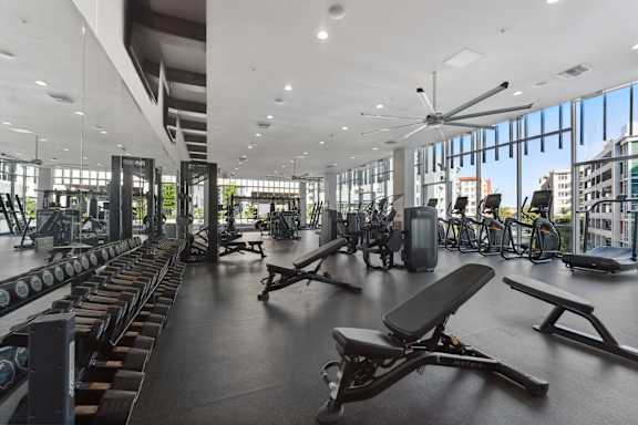 A gym with a variety of equipment including treadmills, weights, and exercise machines.