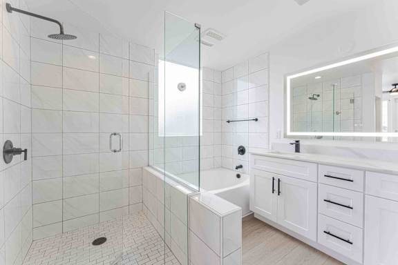 A white bathroom with a glass shower and a white bathtub.