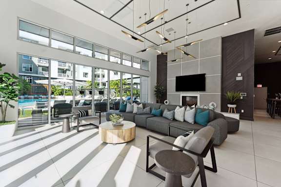A modern living room with a grey sofa and a large window overlooking a pool.