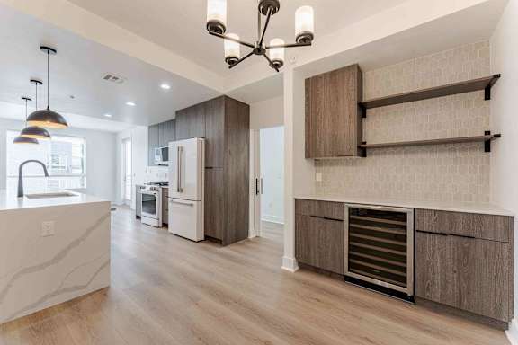 A kitchen with a refrigerator, oven, and a counter with a sink.