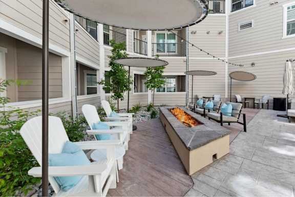 A patio with white chairs and a fire pit.