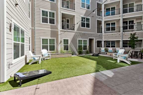 A sunny day at a residential complex with a green lawn and a black table.