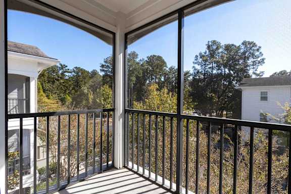 A balcony with a metal railing and a view of trees and houses.