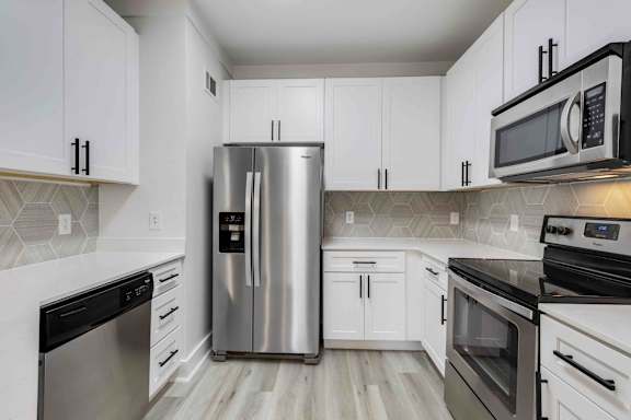 A kitchen with a stainless steel refrigerator and black and white cabinets.