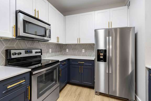 A modern kitchen with dark blue cabinets and stainless steel appliances.