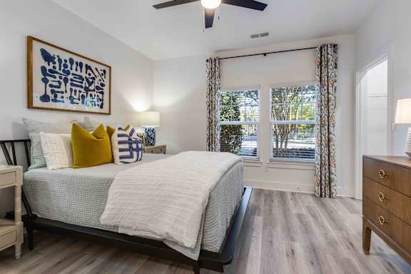 A bedroom with a bed, dresser, and a ceiling fan.
