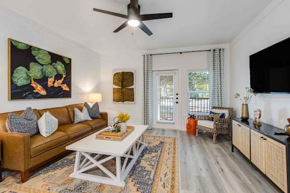 A living room with a brown couch, a white coffee table, and a painting on the wall.