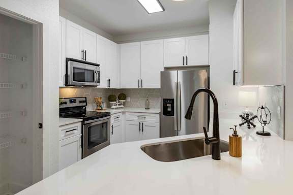 A modern kitchen with a stainless steel refrigerator, microwave, and oven.