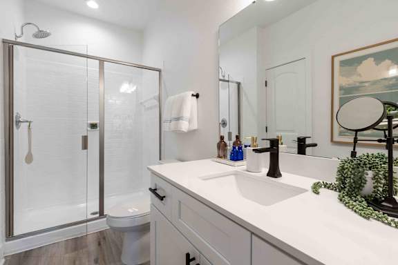 A white bathroom with a glass shower door and a white toilet.