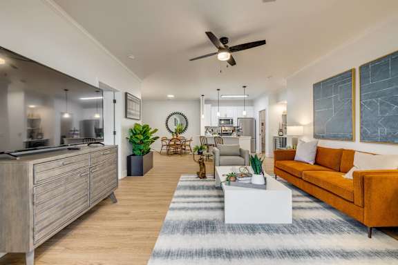 A modern living room with a kitchen area in the background.