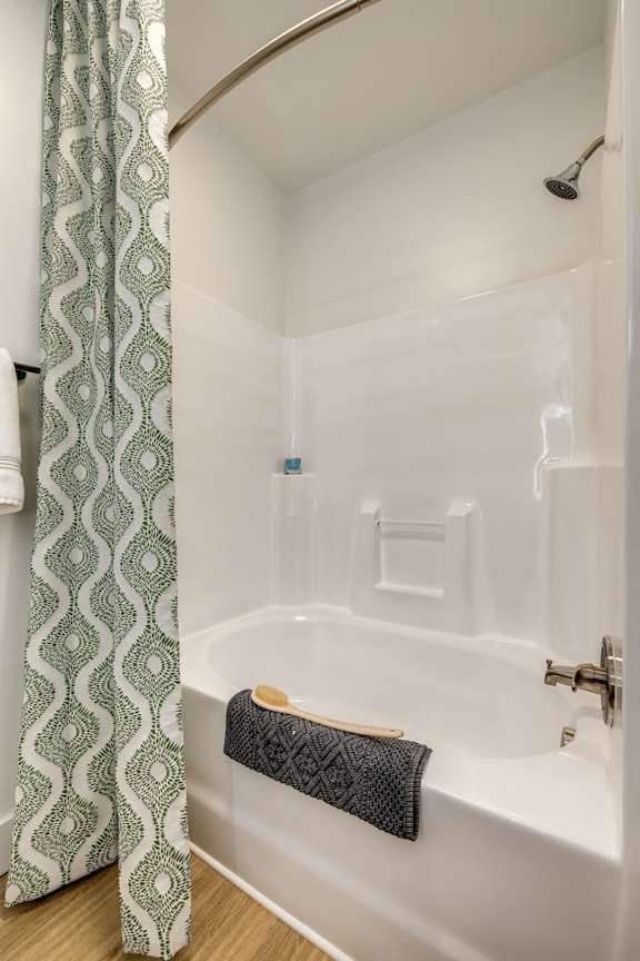 A white bathtub with a black towel on it.