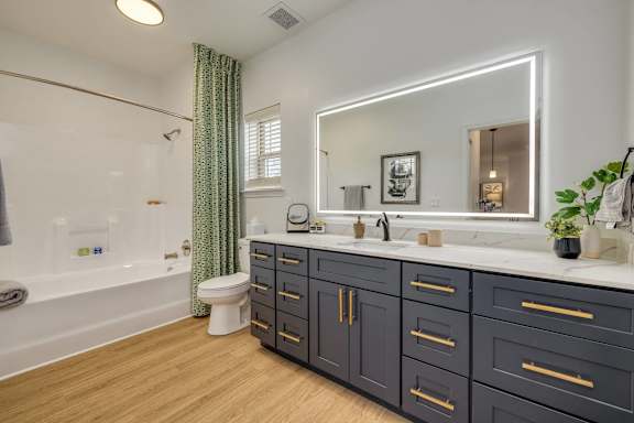A bathroom with a white tub, sink, and a mirror.