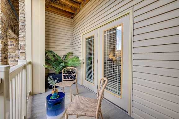 A patio with a chair, table, and potted plant.