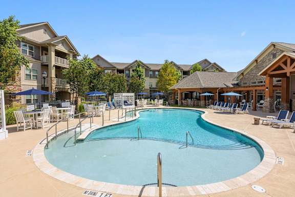 A large outdoor swimming pool surrounded by lounge chairs and umbrellas.