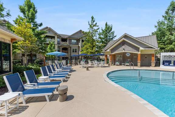A pool area with lounge chairs and a building in the background.