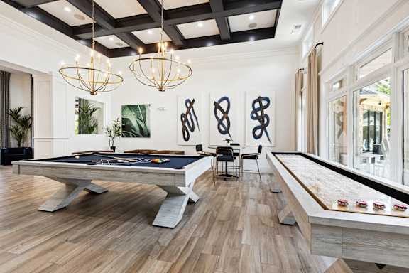 A pool table in a room with a wooden floor and a black and white striped carpet.