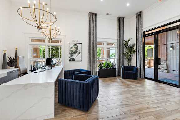 A reception area with a white marble counter and blue chairs.