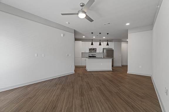 A room with a ceiling fan and a kitchenette.