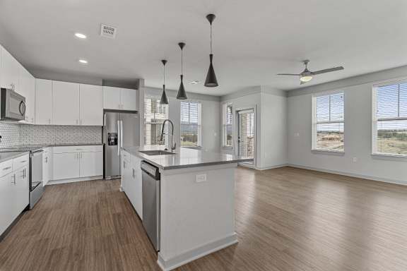 A modern kitchen with white cabinets and a wooden floor.