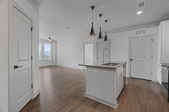 A kitchen with a white island and wooden floors.