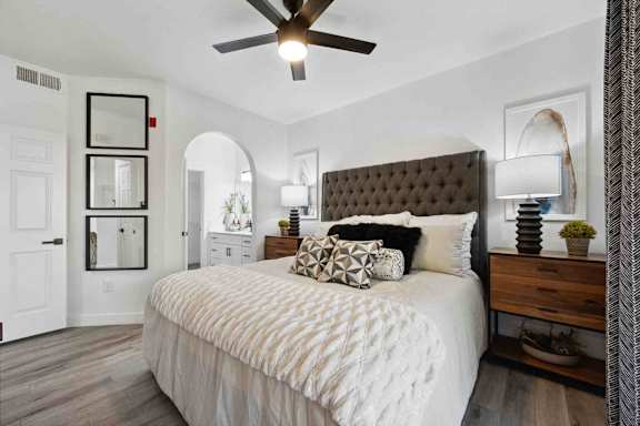 A bedroom with a large bed and a ceiling fan.