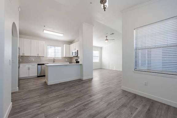 A spacious kitchen with white cabinets and a wooden floor.