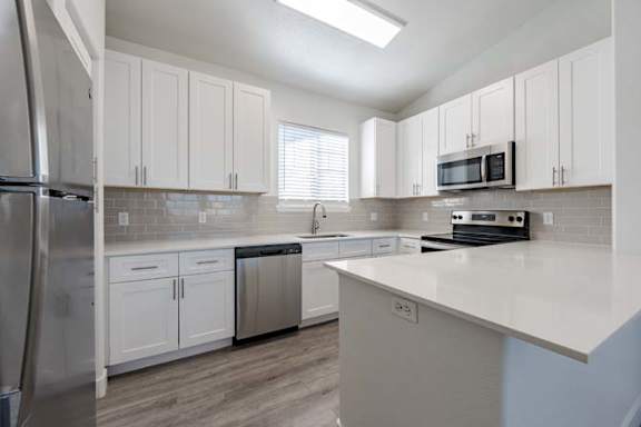 A kitchen with white cabinets and a stainless steel refrigerator.