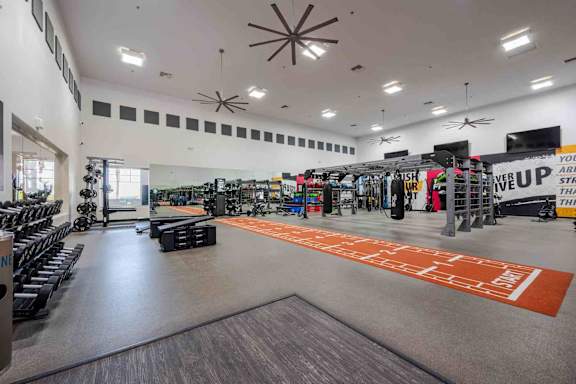 A gym with a variety of equipment including weights and cardio machines.