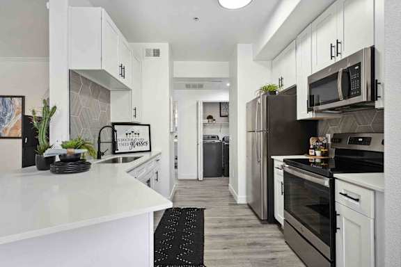 A modern kitchen with white cabinets and stainless steel appliances.