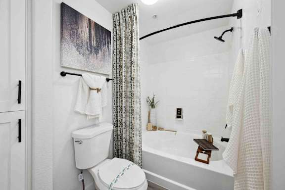 A white toilet sits next to a white bathtub in a bathroom.