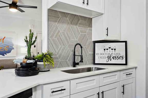 A kitchen with a white countertop and a framed sign that says "My doctor says I need glasses.".