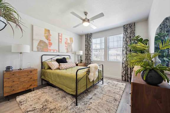 A bedroom with a bed, dresser, and a ceiling fan.