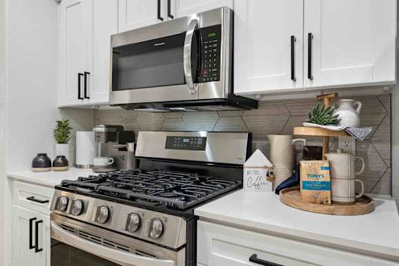 A modern kitchen with a stainless steel stove and a microwave above it.
