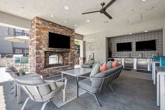 A modern outdoor patio with a fireplace and seating area.