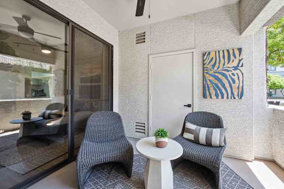A living room with a grey chair and a small table with a plant on it.