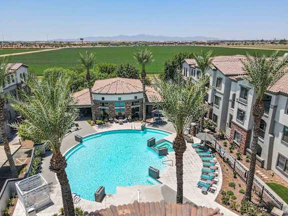 A swimming pool surrounded by palm trees and apartment buildings.