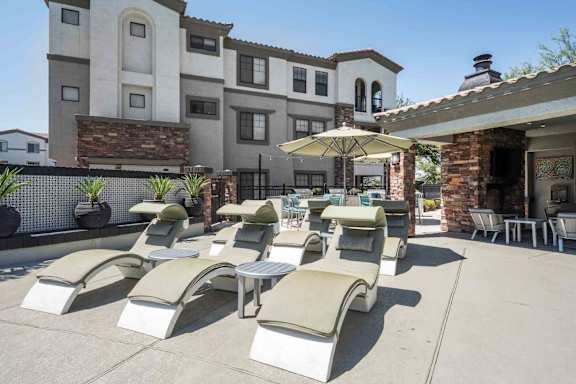 A row of sun loungers are arranged on a patio in front of a building.