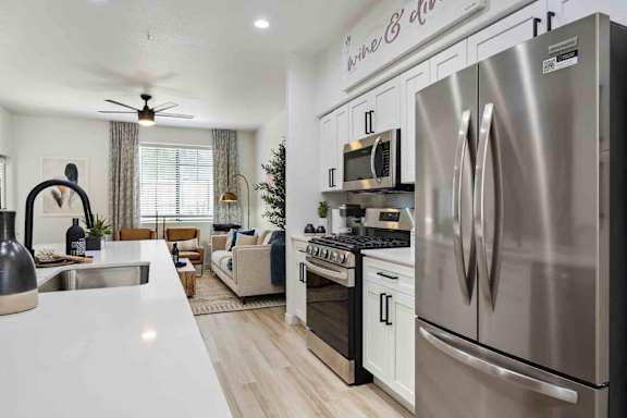 A modern kitchen with stainless steel appliances and a dining area with a couch and chairs.