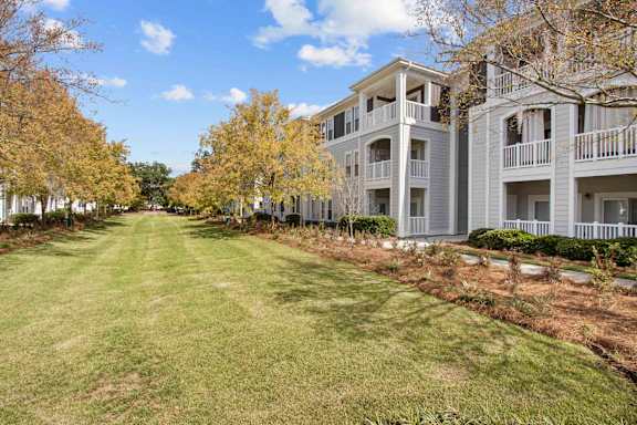 A row of apartment buildings with a grassy lawn in front.