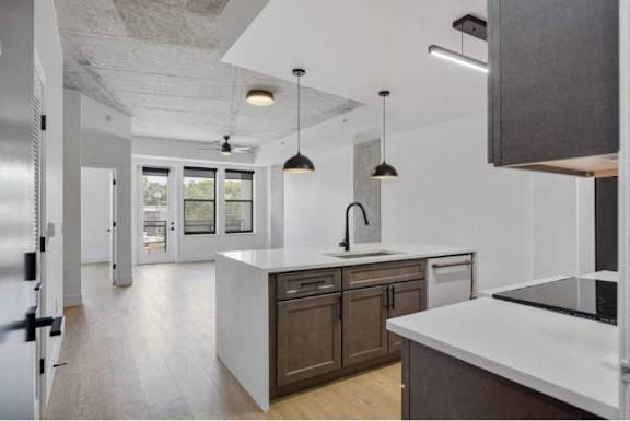 A modern kitchen with a white countertop and dark brown cabinets.