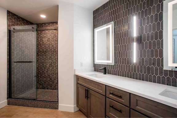A bathroom with a glass shower door and a mirror above a sink.