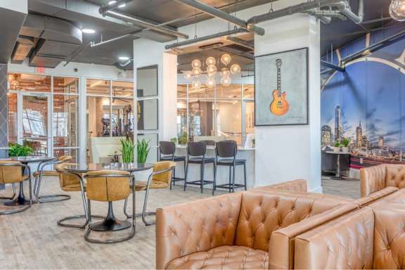 A room with brown leather couches and a guitar poster on the wall.