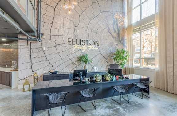 A reception area with a large table and chairs in front of a wall with a tree ring pattern and the word "ELLISON" on it.