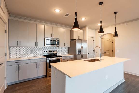 A modern kitchen with a white island and stainless steel appliances.
