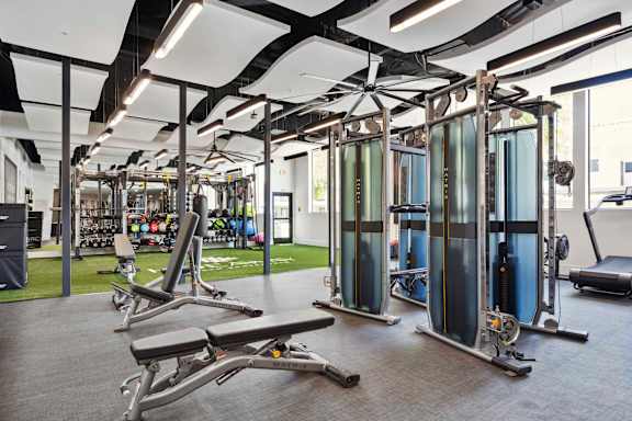 A gym with a variety of equipment including treadmills, weights, and exercise machines.