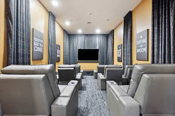 A home theater with grey seats and a black screen.