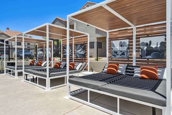 A row of sun loungers are arranged on a patio.