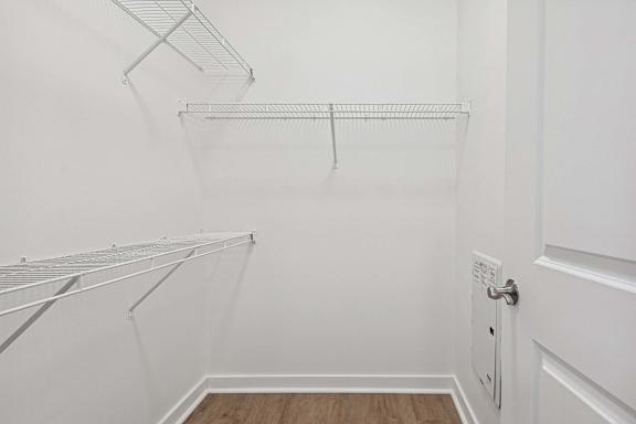 A white closet with a door and shelves.